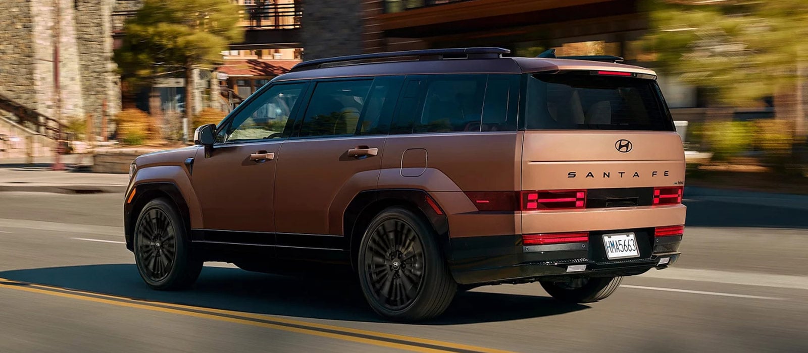 A brown Hyundai Santa Fe driving through a town.
