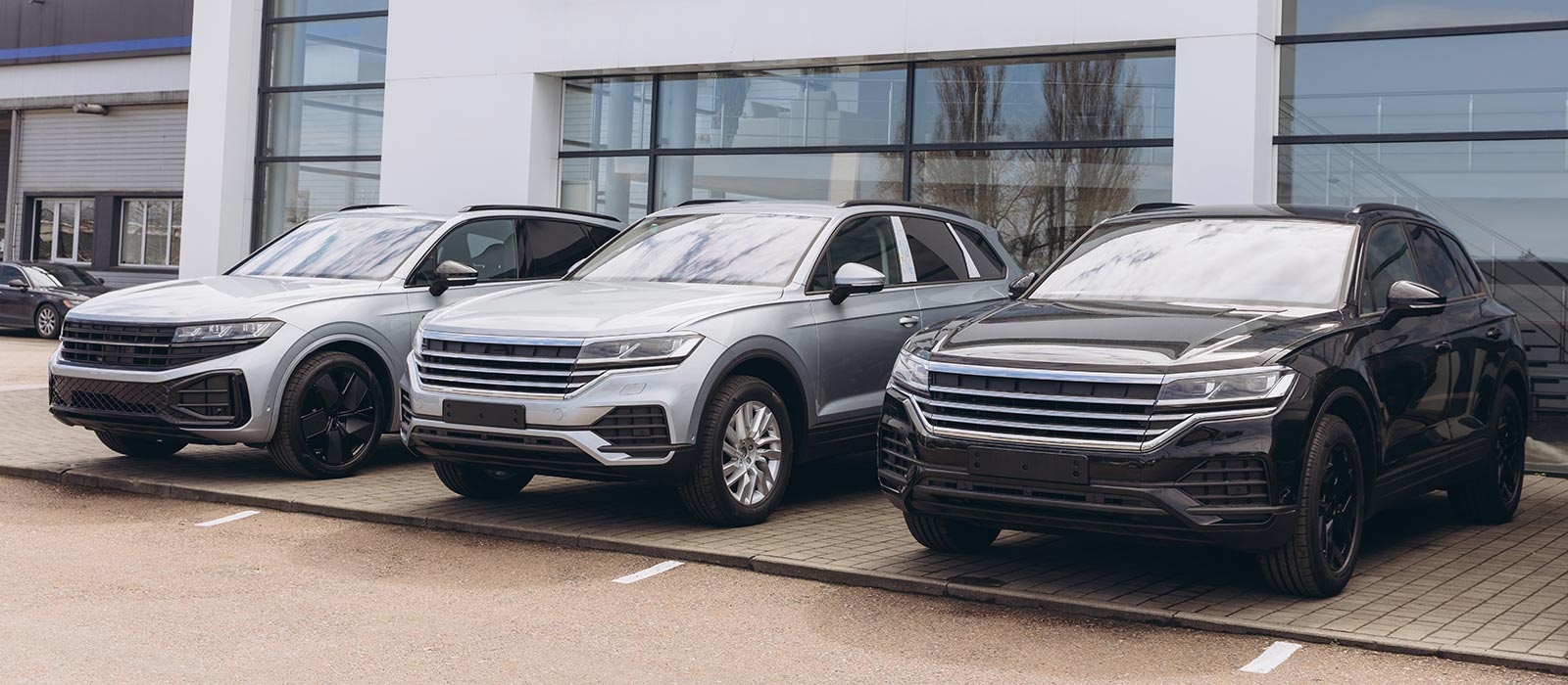 A trio of SUVs parked in front of a car dealership.